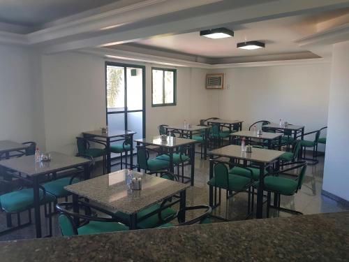 a dining room with tables and green chairs at Flat Saint Paul Residence in Bauru