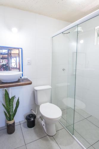 a bathroom with a toilet and a glass shower at Morada Amazona in Praia do Rosa