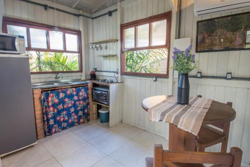 a kitchen with a table and a stove and windows at Morada Amazona in Praia do Rosa