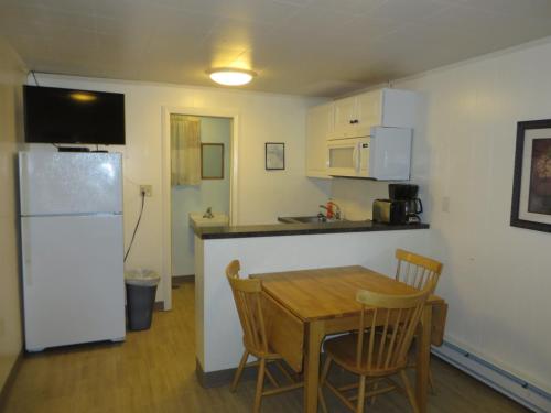 a kitchen with a table and a white refrigerator at Elmwood Motor Court in Old Orchard Beach