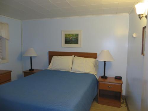 a bedroom with a blue bed and two lamps at Elmwood Motor Court in Old Orchard Beach