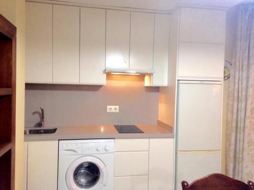 a kitchen with a washing machine and a refrigerator at Apartamentos vista a tres continentes in La Línea de la Concepción