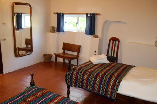 Un dormitorio con una cama, un espejo y una silla. en Monte da contenda, en Campo Maior