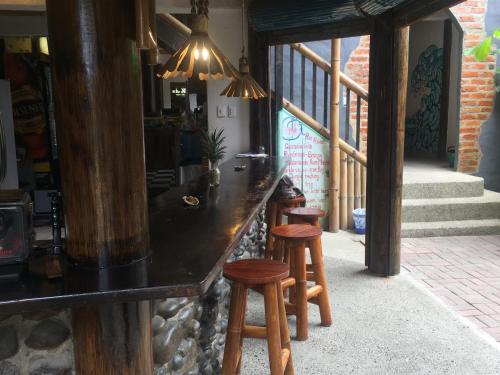 a bar with wooden stools in a room at La Facha Hostal Restaurant Surf in Mompiche