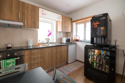 a kitchen with wooden cabinets and a black refrigerator at Mocho GuestHouse in São Mamede