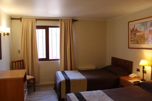 a hotel room with two beds and a window at Hotel Diego de Almagro San Pedro De Atacama in San Pedro de Atacama
