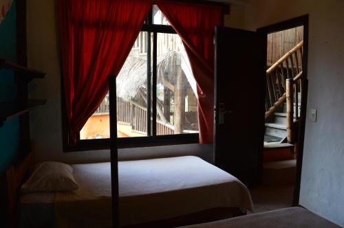 a bedroom with a bed and a window and a staircase at La Facha Hostal Restaurant Surf in Mompiche