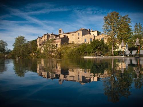 a castle sitting on top of a hill next to a lake at Castel Monastero - The Leading Hotels of the World in Castelnuovo Berardenga
