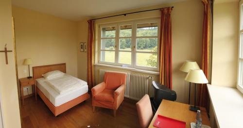 een slaapkamer met een bed, een stoel en een raam bij Malteser Kommende in Engelskirchen