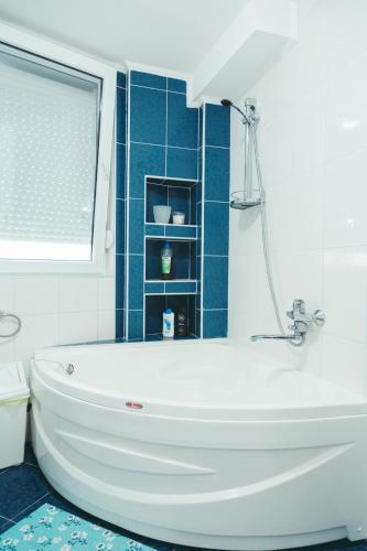 a white bath tub in a bathroom with blue tiles at Apartment Fila in Kochani