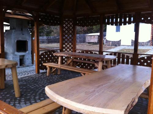a wooden table and benches in a pavilion with a fireplace at Vila Sport Borsec in Borsec
