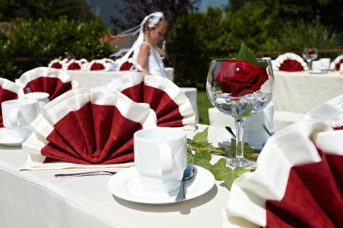 a table with red and white plates and a red rose at Berghotel Hammersbach in Grainau