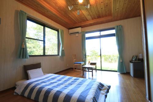 a bedroom with a bed with a blue and white comforter at Minshuku nicoichi in Yakushima