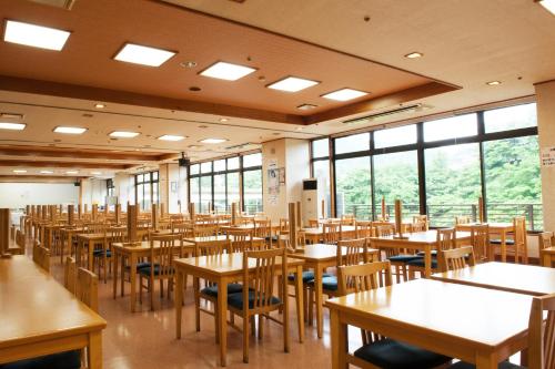 a dining room with tables and chairs and windows at Hotel New Ohruri in Nikko