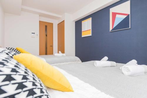 a bedroom with two beds and a blue wall at Nishi-shinjuku Hotel Apartment in Tokyo