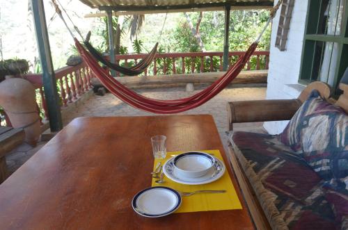a wooden table with plates and glasses and a hammock at Hacienda Gonzabal in Loja