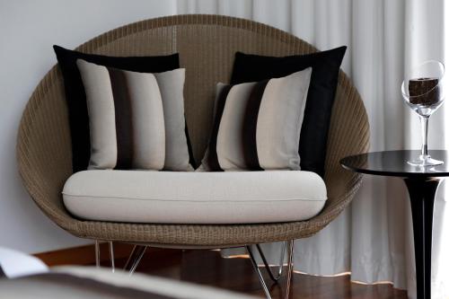 a rattan chair with pillows and a glass of wine at LBV House Hotel in Pinhão