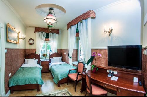 a bedroom with two beds and a desk and a television at Willa Różana in Nałęczów