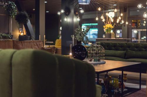 a living room with green couches and a table at Best Western Plus Hus 57 in Ängelholm