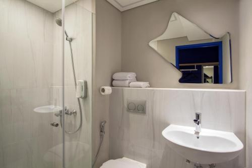 een badkamer met een douche, een wastafel en een toilet bij ibis budget Surabaya Diponegoro in Surabaya