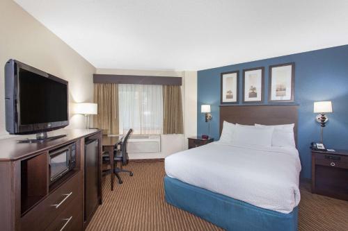 a hotel room with a bed and a flat screen tv at AmericInn by Wyndham Mankato Event Center near MSU in Mankato