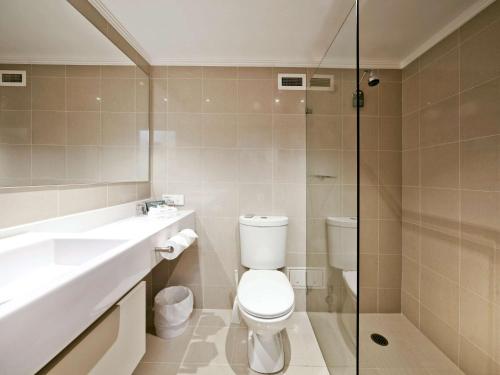 a bathroom with a toilet and a sink and a shower at Mercure Canberra in Canberra