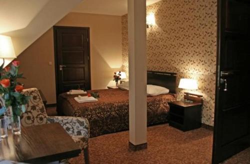 a hotel room with a bed and a chair at Zajazd Kmicic in Zemborzyce Dolne