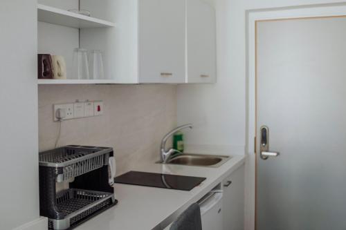 a small kitchen with white cabinets and a sink at River View Boutique Apts in Ayia Napa