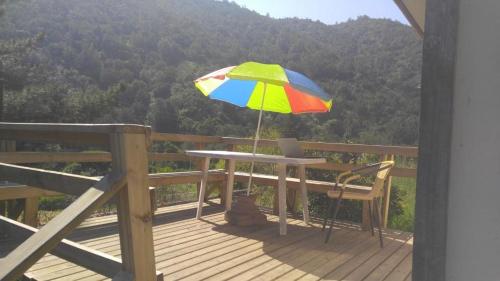 a table with a colorful umbrella on a deck at Refugios Olmue Santa Teresa in El Maqui
