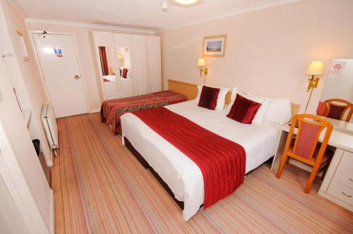 a hotel room with two beds and a desk at Denewood Hotel in Bournemouth