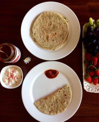 two white plates with food on a table with fruit at The Xanadu Meghadootam in Kodaikānāl