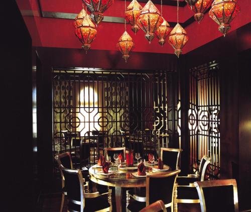 a dining room with a table and chairs and chandeliers at Miramar Al Aqah Beach Resort in Al Aqah