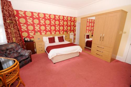 a bedroom with a bed and a couch and a chair at Denewood Hotel in Bournemouth