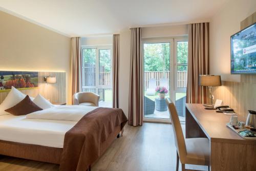 a hotel room with a bed and a desk at Best Western Plus Parkhotel Erding in Erding