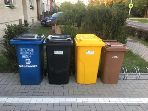 four trash cans lined up in a row on a sidewalk at Penzion U Hujňáků in Rohatec