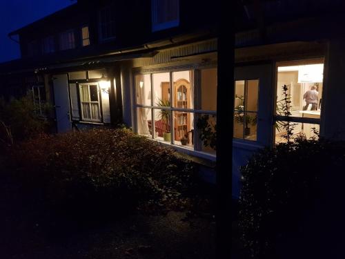 a house with windows at night with a man standing outside at Hotel Schleimünde in Kappeln