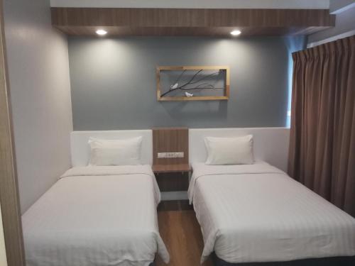 two beds in a room with white sheets at Shade House - Bitec Bangna in Bangkok