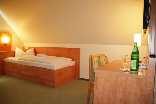 ein Schlafzimmer mit einem Bett und einem Tisch mit einer Flasche in der Unterkunft Gasthof zur Mühle in Kirchhatten