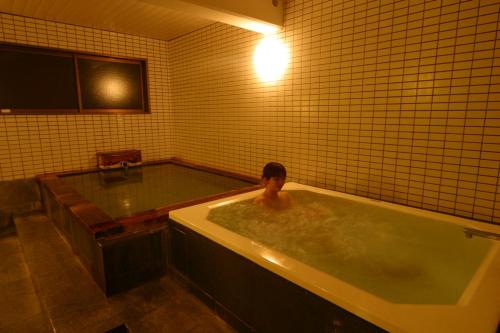 a person in a bath tub in a bathroom at Pension Raisin in Kusatsu