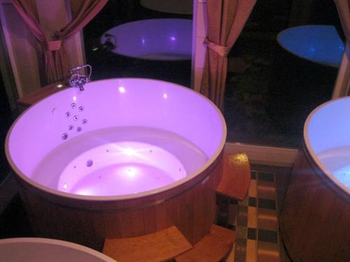 uma grande banheira de madeira na casa de banho com WC em Hotel Księżycowy Dworek em Ketrzyn