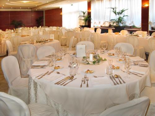 a banquet hall with white tables and white chairs at Hotel Ristorante Ala d'Oro in Lugo