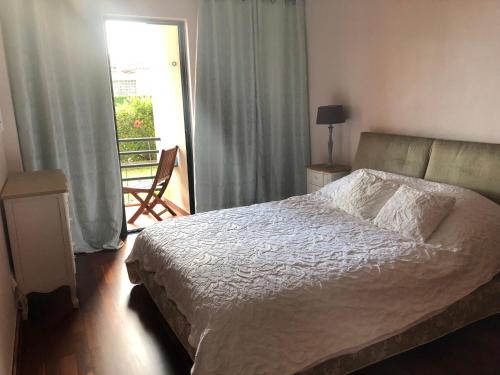 a bedroom with a bed and a window with a balcony at Varandas do Funchal in Funchal