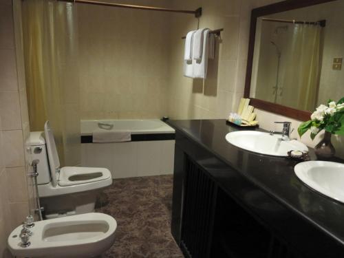 a bathroom with a toilet and two sinks and a mirror at KMA Bagan Hotel River View in Bagan