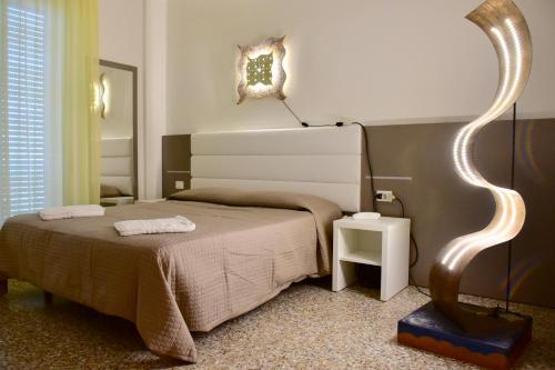 a bedroom with a bed and a lamp on the wall at Hotel Astoria in Pesaro