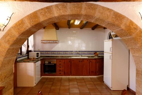 a kitchen with an archway in a kitchen with a refrigerator at Casa Rural Mas de Sant Pau - Turistrat. in Albocácer