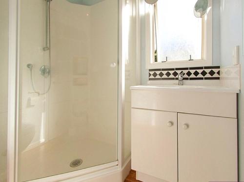a white bathroom with a shower and a sink at Pretty on Paku, Tairua - Cottage in Tairua