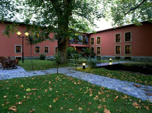 a large pink building with a tree in the yard at Parador de Gijón in Gijón