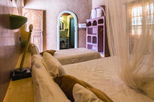 a bedroom with two beds with curtains on them at Riad Dar Ouzine in Merzouga
