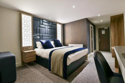 a bedroom with a large bed with blue pillows at Hetland Hall Hotel in Dumfries