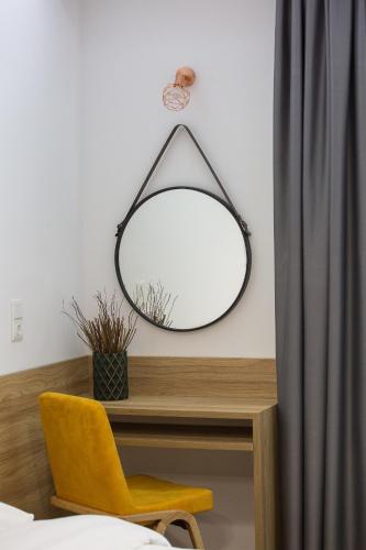 a mirror on a wall above a desk with a yellow chair at Alexandros in Giannitsa